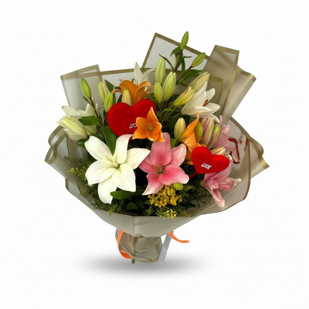 A vibrant mixed flower bouquet wrapped in metallic gold paper, featuring white lilies, pink lilies, orange tulips, red heart-shaped carnations, and green foliage on a white background.